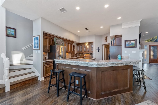 kitchen with stainless steel fridge, a breakfast bar, a spacious island, pendant lighting, and dark hardwood / wood-style floors