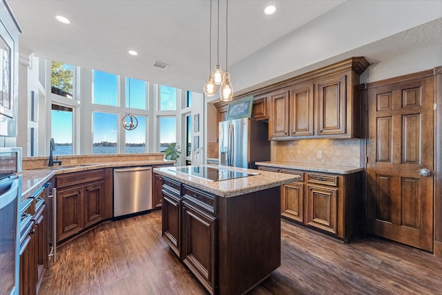 kitchen featuring pendant lighting, sink, decorative backsplash, a kitchen island, and stainless steel appliances