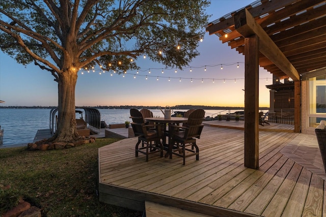 deck at dusk featuring a water view