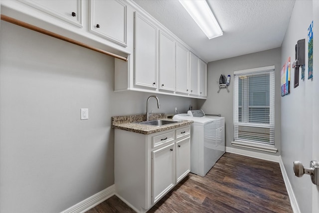 clothes washing area featuring sink, dark wood-type flooring, cabinets, a textured ceiling, and washer and clothes dryer