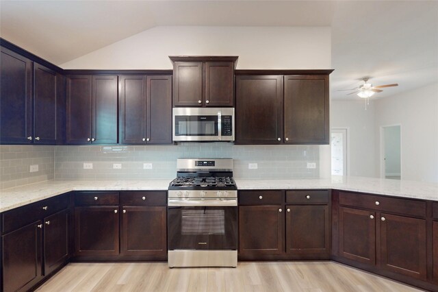 19818 Paros Island Dr, Hockley, TX 77447 - kitchen featuring stainless steel appliances, light wood finished floors, ceiling fan, vaulted ceiling, and light stone counters