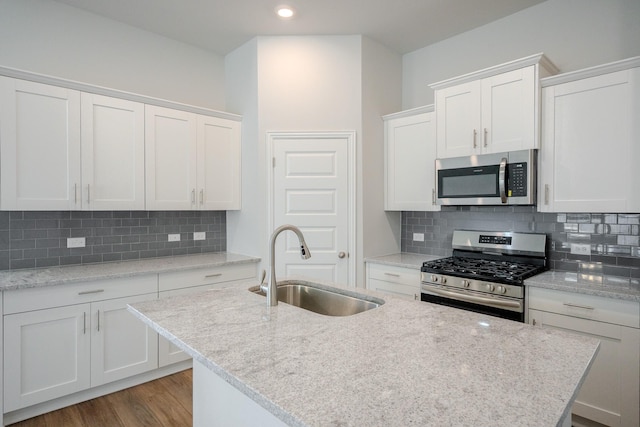 22207 Kastoria Dr, Hockley, TX 77447 - kitchen with appliances with stainless steel finishes, an island with sink, white cabinets, backsplash, and recessed lighting