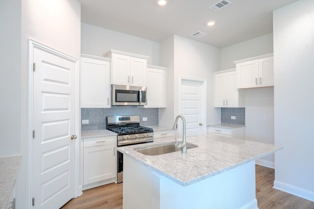 22207 Kastoria Dr, Hockley, TX 77447 - kitchen featuring stainless steel appliances, light wood-style flooring, tasteful backsplash, white cabinetry, and recessed lighting