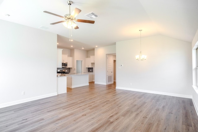 22207 Kastoria Dr, Hockley, TX 77447 - unfurnished living room featuring a chandelier, ceiling fan, light wood-style floors, and vaulted ceiling