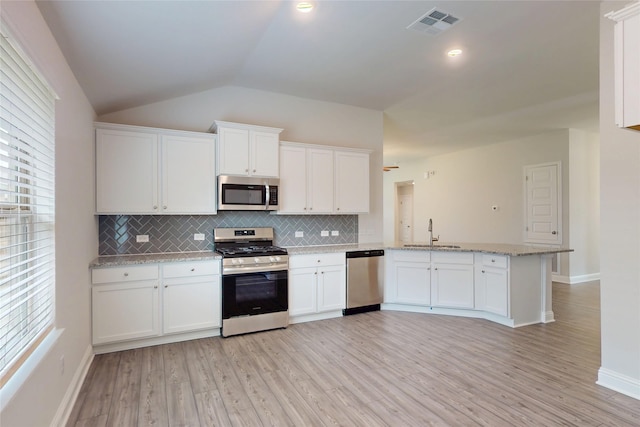 19814 Paros Island Dr, Hockley, TX 77447 - kitchen featuring stainless steel appliances, tasteful backsplash, white cabinetry, vaulted ceiling, and a peninsula