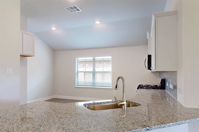 19814 Paros Island Dr, Hockley, TX 77447 - kitchen with stove, light stone counters, lofted ceiling, stainless steel microwave, and white cabinets