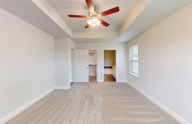 19814 Paros Island Dr, Hockley, TX 77447 - unfurnished bedroom with a tray ceiling, light colored carpet, a walk in closet, and a ceiling fan