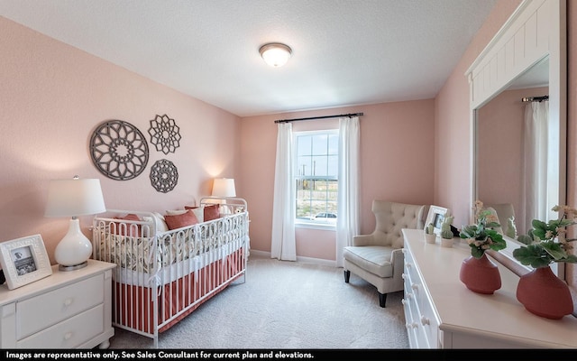 bedroom featuring a crib, light carpet, and a textured ceiling