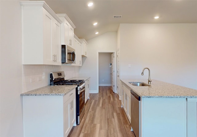 kitchen with visible vents, backsplash, light wood-style flooring, appliances with stainless steel finishes, and a sink