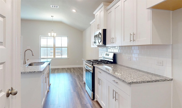 kitchen featuring lofted ceiling, wood finished floors, a sink, visible vents, and appliances with stainless steel finishes