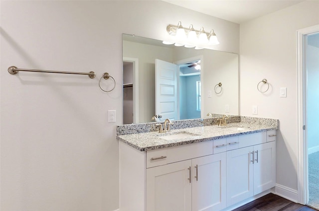 bathroom with a ceiling fan, a sink, baseboards, and double vanity