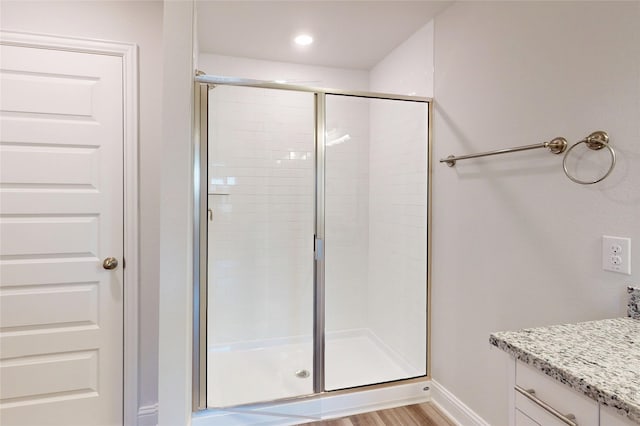 bathroom featuring a stall shower, baseboards, wood finished floors, and vanity