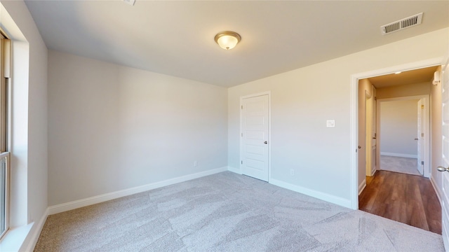 unfurnished bedroom with a closet, carpet flooring, visible vents, and baseboards