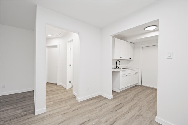 hallway with light wood-type flooring and sink