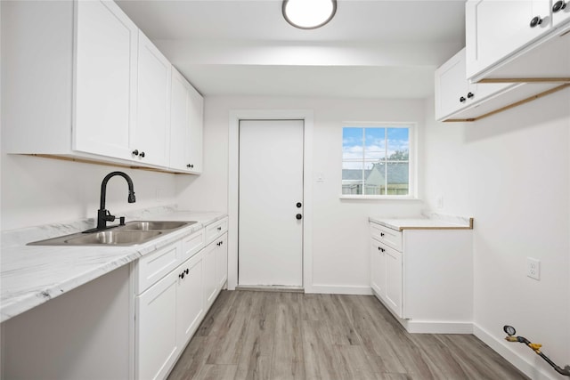 laundry area with light hardwood / wood-style floors and sink