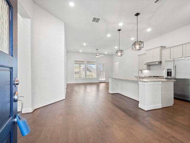 kitchen featuring stainless steel fridge, ceiling fan, a kitchen island with sink, and dark hardwood / wood-style floors