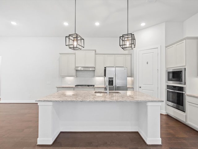 kitchen featuring a center island with sink, pendant lighting, light stone countertops, and stainless steel appliances