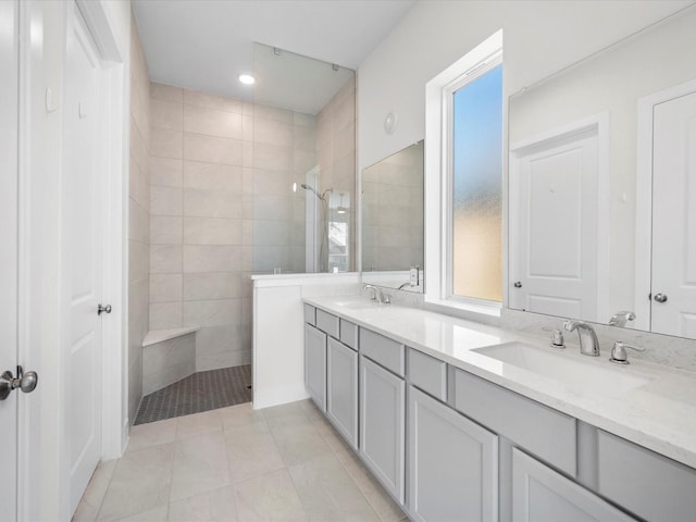 bathroom featuring tile patterned flooring, a tile shower, and vanity