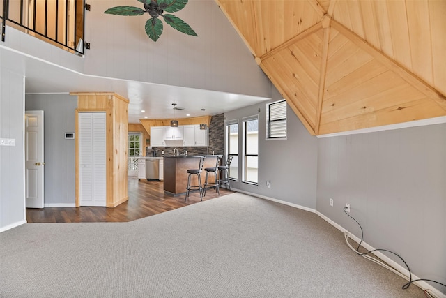 living room featuring high vaulted ceiling, dark wood-type flooring, and wood walls