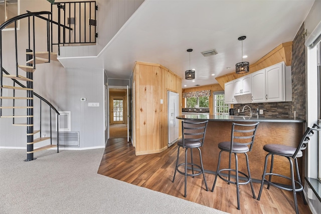 kitchen with backsplash, dark wood-type flooring, a kitchen breakfast bar, kitchen peninsula, and white cabinetry