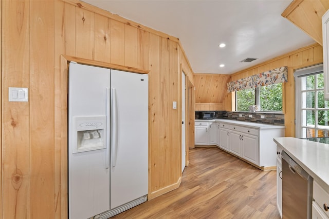 kitchen with tasteful backsplash, wooden walls, light hardwood / wood-style flooring, dishwasher, and white fridge with ice dispenser