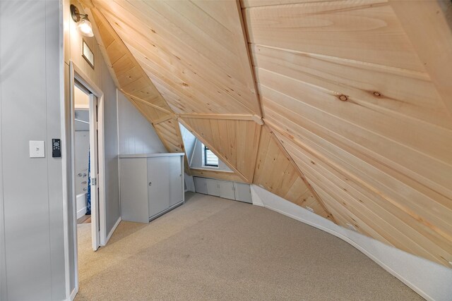 additional living space with light carpet, vaulted ceiling, and wooden walls