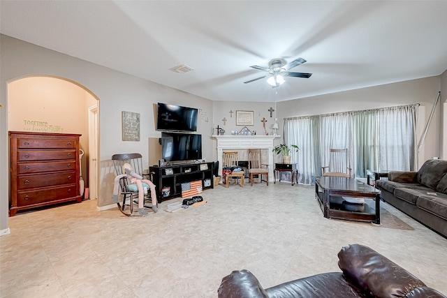 living room with ceiling fan and a tiled fireplace