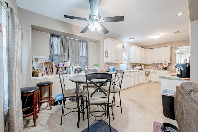 tiled dining space with plenty of natural light and ceiling fan