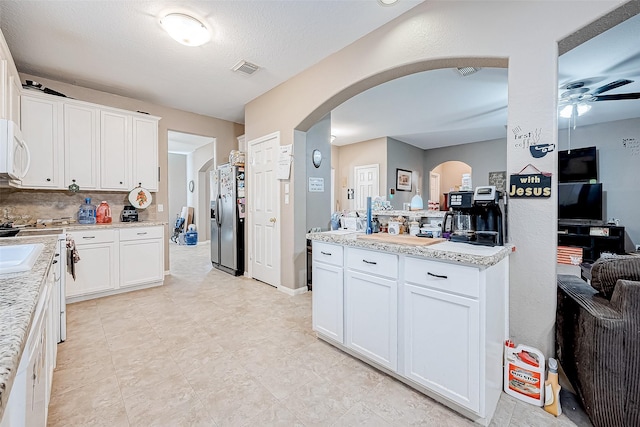 kitchen featuring backsplash, ceiling fan, white cabinetry, and stainless steel refrigerator with ice dispenser