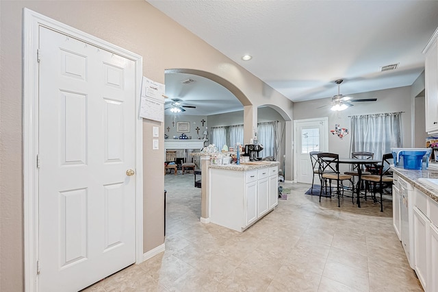 kitchen featuring white cabinets, light tile patterned flooring, light stone countertops, and ceiling fan