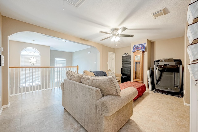 tiled living room with ceiling fan and a textured ceiling