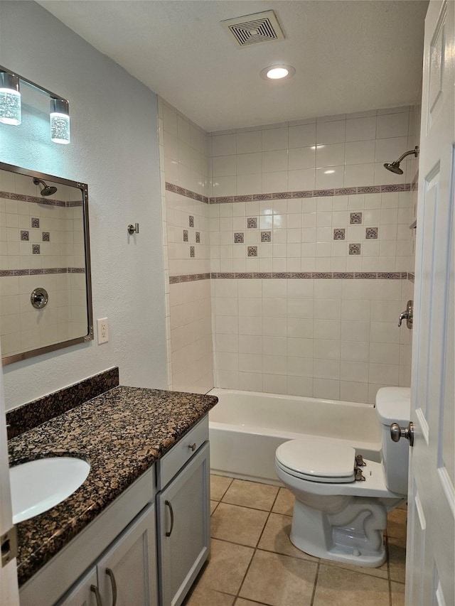 full bathroom with tiled shower / bath combo, tile patterned flooring, a textured ceiling, toilet, and vanity