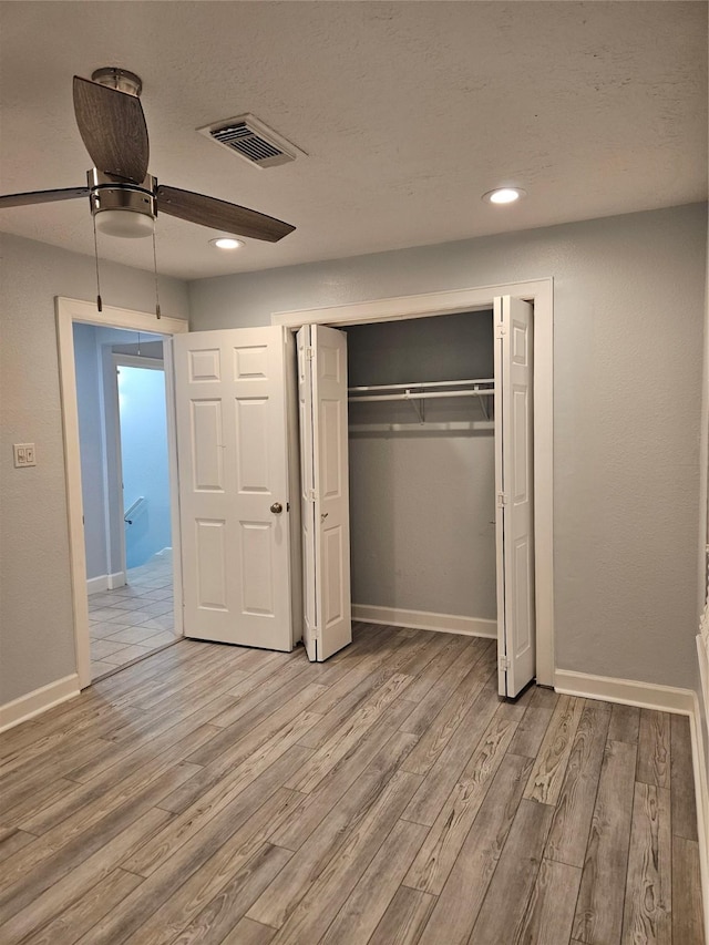 unfurnished bedroom with ceiling fan, light hardwood / wood-style floors, and a closet