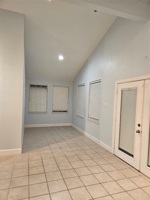 tiled spare room with high vaulted ceiling