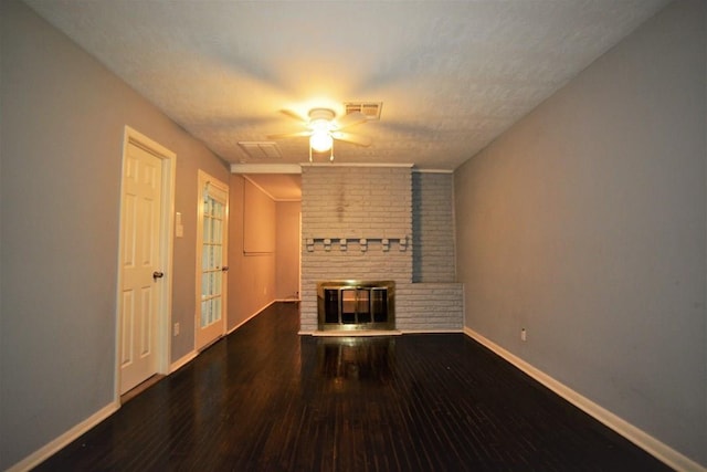 unfurnished living room with a fireplace, ceiling fan, dark hardwood / wood-style flooring, and a textured ceiling