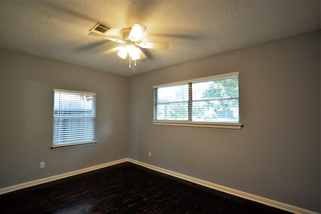 unfurnished room with a wealth of natural light, ceiling fan, wood-type flooring, and a textured ceiling