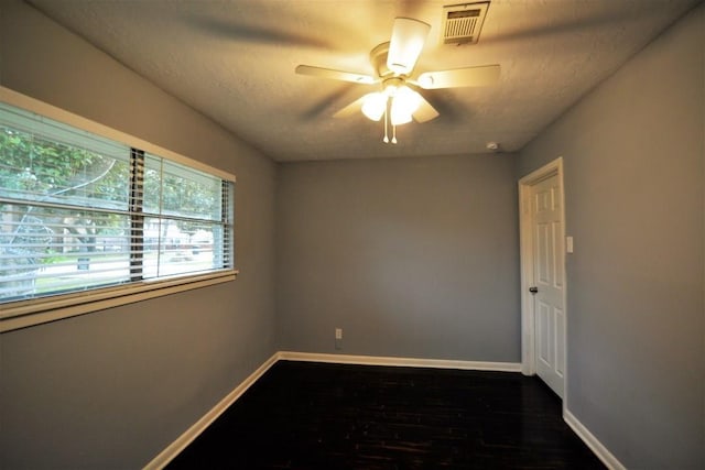 unfurnished room with ceiling fan, a textured ceiling, and dark wood-type flooring