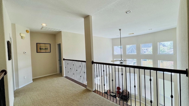 hallway with light colored carpet and a textured ceiling