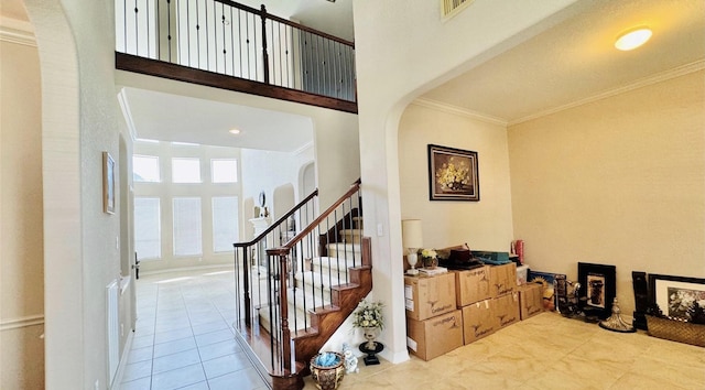 foyer featuring a high ceiling, ornamental molding, and light tile patterned flooring