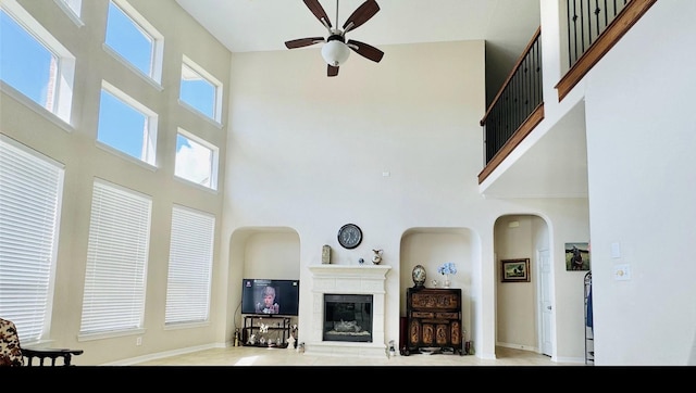 tiled living room with ceiling fan and a towering ceiling