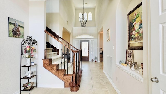 foyer entrance featuring light tile patterned floors, a towering ceiling, and a notable chandelier