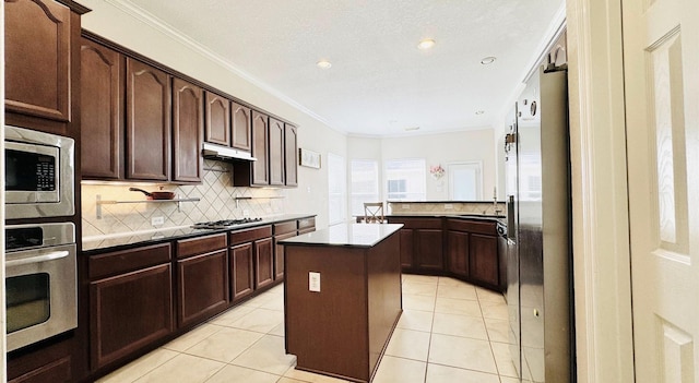 kitchen featuring ornamental molding, dark brown cabinets, stainless steel appliances, light tile patterned floors, and a center island