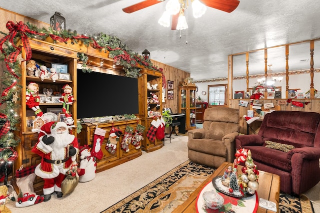 living room with carpet flooring, wood walls, ceiling fan, and a textured ceiling