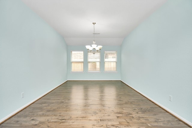 unfurnished dining area featuring a chandelier, wood-type flooring, and vaulted ceiling