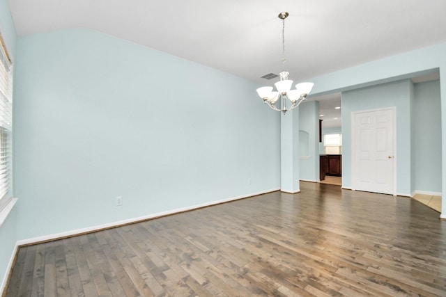 spare room featuring a chandelier and dark wood-type flooring