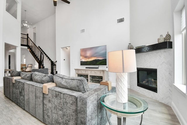 living room featuring ceiling fan, a high ceiling, and light wood-type flooring