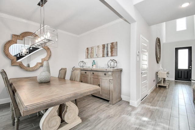 dining space with ornamental molding and light hardwood / wood-style flooring