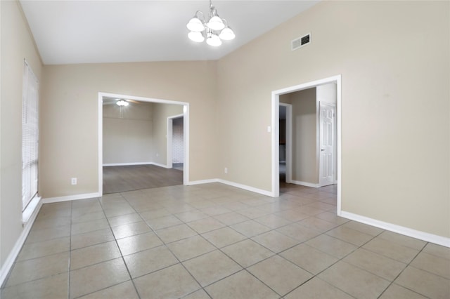 tiled empty room with ceiling fan with notable chandelier and vaulted ceiling