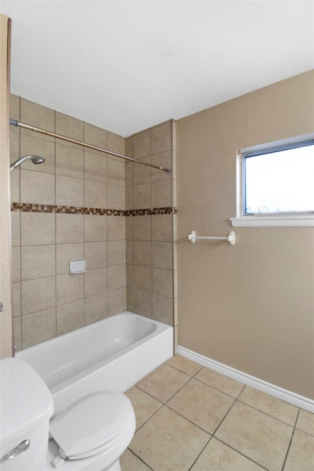 bathroom featuring tile patterned flooring, tiled shower / bath combo, and toilet