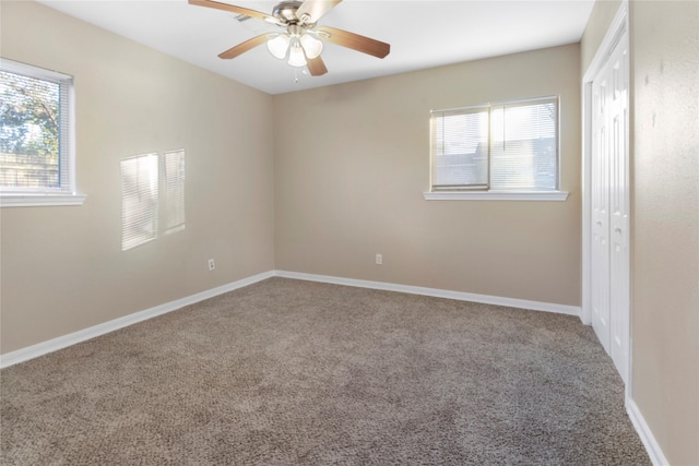 carpeted spare room featuring ceiling fan and a healthy amount of sunlight